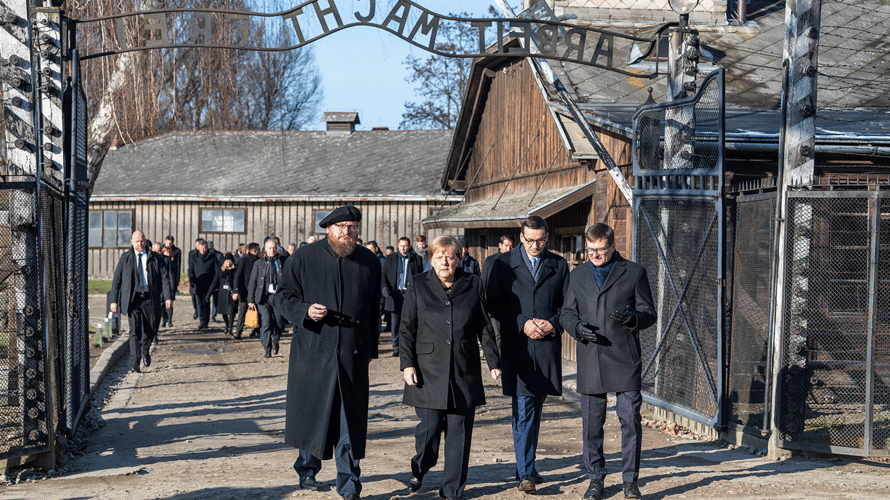 Bundeskanzlerin Angela Merkel besucht das ehemalige deutsche Konzentrationslager Auschwitz und geht zusammen mit dem polnischen Ministerpräsidenten Mateusz Morawiecki (rechts neben Merkel) und dem Direktor der Gedenkstätte und Präsidenten der Stiftung Auschwitz-Birkenau, Piotr Cywinski (links neben Merkel), durch das Eingangstor mit dem Schriftzug "Arbeit macht frei". Ganz rechts geht Andrzej Kacorzyk, Vizedirektor de Museums Auschwitz-Birkenau. Foto: picture alliance/Robert Michael/dpa-Zentralbild/dpa