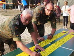 Hauptmann Weber und Stabsfeldwebel a.D. Reiche unterschreiben die Schleife, bevor diese auf die Reise geht Foto: Privat/Bachmann