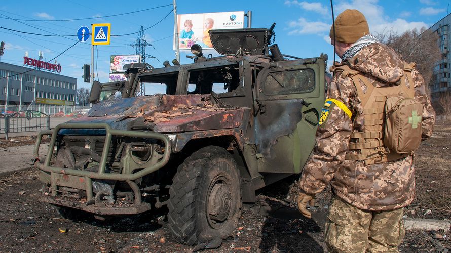 In Charkiw steht ein ukrainischer Soldat vor einem zerstörten russischen Fahrzeug. Seit einer Woche ist Krieg in Europa. Foto: picture alliance / Associated Press / Marienko Andrew