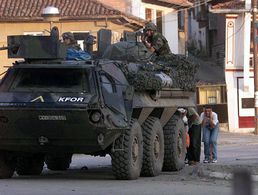 Einsatz im Kosovo: Zivilisten suchen am 13. Juni 1999 in Prizren Deckung hinter einem Transportpanzer der Bundeswehr. Bei dem Schusswechsel kommen zwei bewaffnete serbische Angreifer ums Leben. Foto: picture-alliance/dpa/AFP Christophe Simon