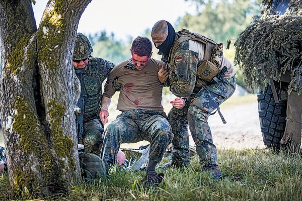 Soldaten helfen einem verletzten Kameraden auf die Beine. Bei den Informationslehrübungen zeigt der Sanitätsdienst der Bundeswehr regelmäßig seine Fähigkeiten. Ein besonderes Augenmerk liegt auf den Ebenen 1 und 2 der sogenannten Rettungskette. Foto: Bundeswehr/Anna Derr 