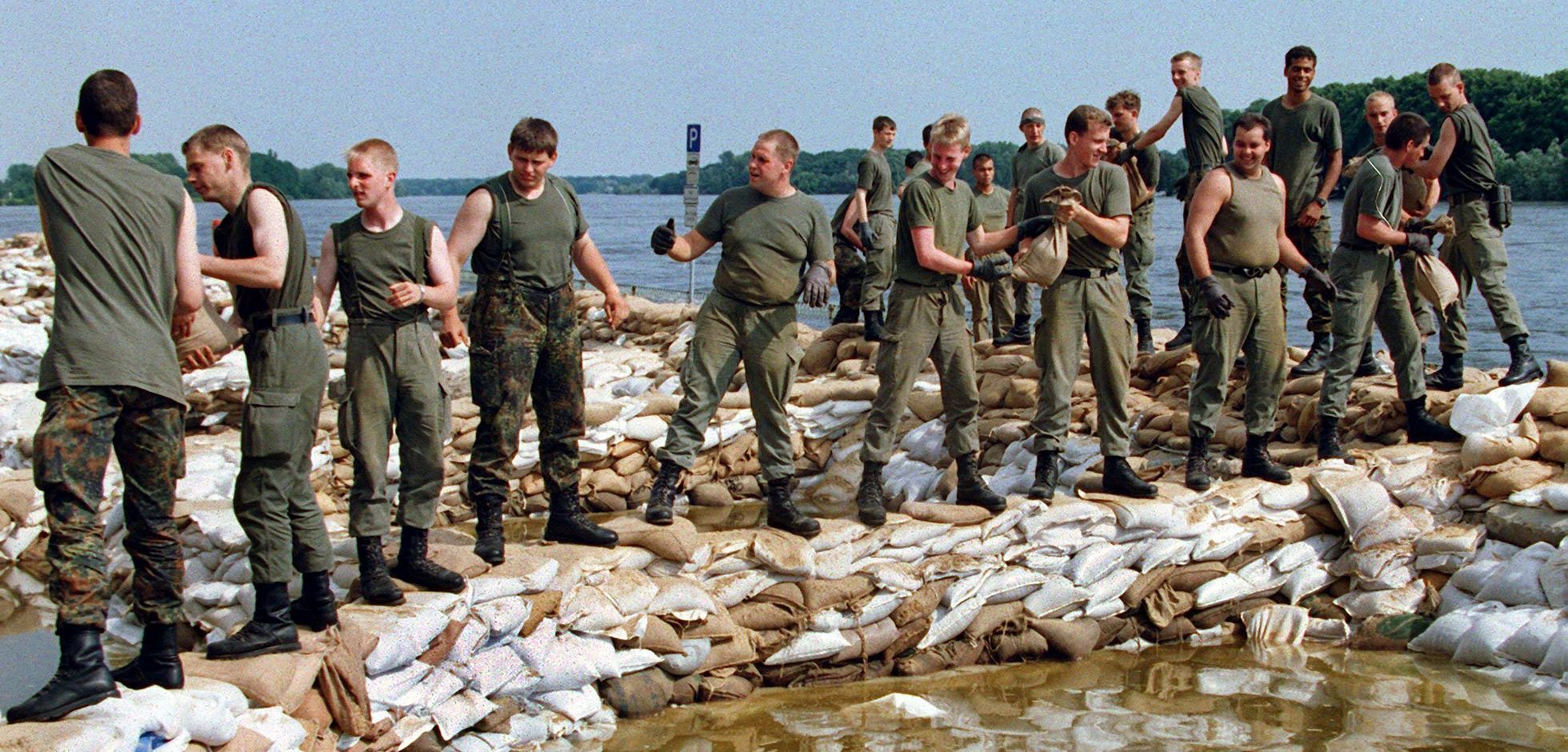 Pausenlos stapeln Bundeswehrsoldaten am 27.7.1997 in Frankfurt (Oder) Sandsäcke, um den künstlichen Deich an der Oder zu erhöhen. Die Hilfskräfte von Bundeswehr, Bundesgrenzschutz, Technischem Hilfswerk (THW) und der freiwilligen Feuerwehren arbeiten  im Hochwassergebiet Hand in Hand. Foto: dpa/Wolfgang Kumm