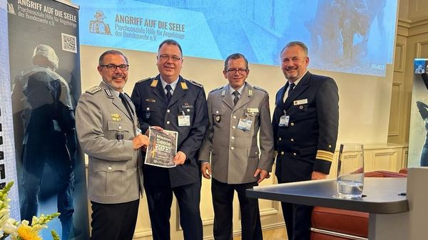 Oberstabsfeldwebel Stefan Sprengers (l.), Stabsfeldwebel Thomas Schwappacher (2.v.r.) und Fregattenkapitän Marco Thiele (r.) überreichten Stabsfeldwebel Frank Eggen das DBwV-Forderungspapier "Mission Seele 2023". Foto: DBwV/Katja Gersemann