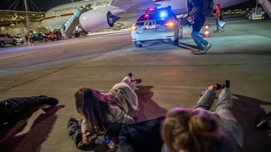 Personen liegen auf dem Flughafen von Tel Aviv vor dem Luftwaffen-Airbus von Bundeskanzler Scholz auf dem Boden. Die Delegation des Bundeskanzlers hatte vor dem Abflug nach Kairo wegen eines Raketenalarms schlagartig das Flugzeug verlassen müssen. Foto: picture alliance/dpa Pool/Michael Kappeler