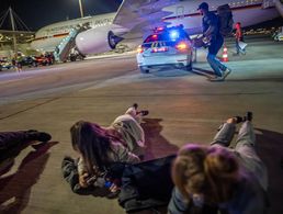 Personen liegen auf dem Flughafen von Tel Aviv vor dem Luftwaffen-Airbus von Bundeskanzler Scholz auf dem Boden. Die Delegation des Bundeskanzlers hatte vor dem Abflug nach Kairo wegen eines Raketenalarms schlagartig das Flugzeug verlassen müssen. Foto: picture alliance/dpa Pool/Michael Kappeler