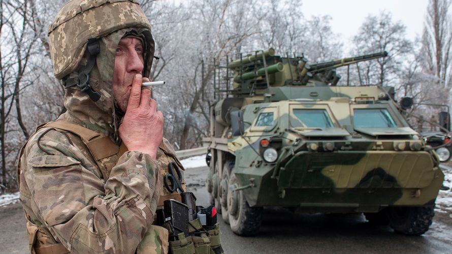 Ein ukrainischer Soldat raucht nahe der Stadt Charkiw neben einem Schützenpanzer eine Zigarette. Das Gebiet um die Stadt im Nordosten des Landes, unweit der Grenze zu Russland, ist seit Beginn der russischen Aggression schwer umkämpft. Foto: picture alliance / ASSOCIATED PRESS / Andrew Marienko